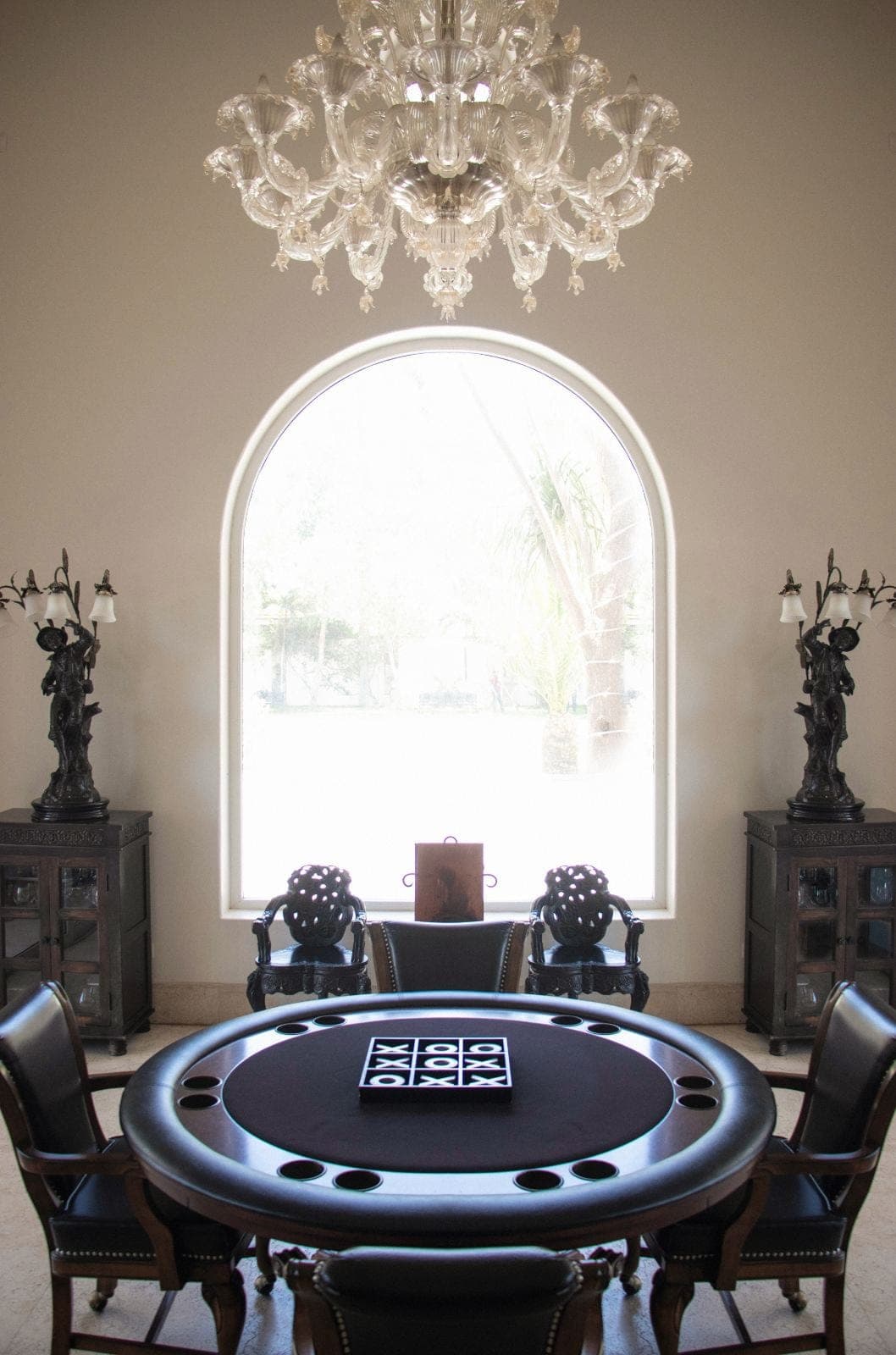 Salón de juegos con candelabro de cristal y ventanal de arco