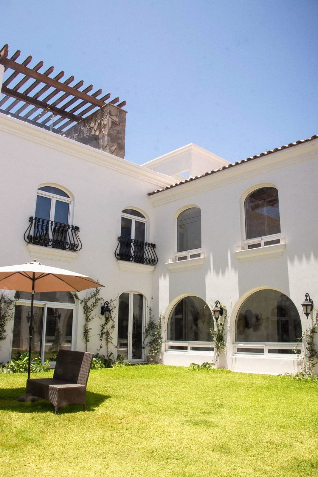 Patio interior de La Casona: arcos, balcones de herrería y pérgola